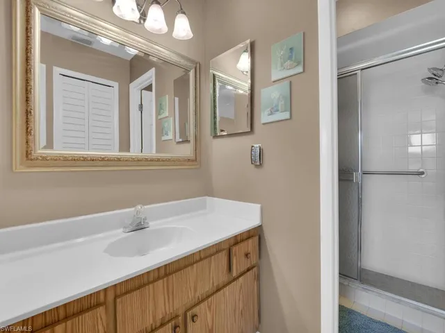 Bathroom featuring a stall shower, vanity, and a chandelier