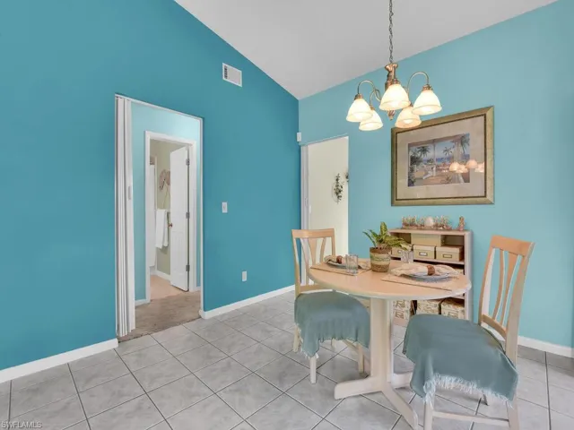 Dining area featuring a chandelier, light tile patterned flooring, and high vaulted ceiling
