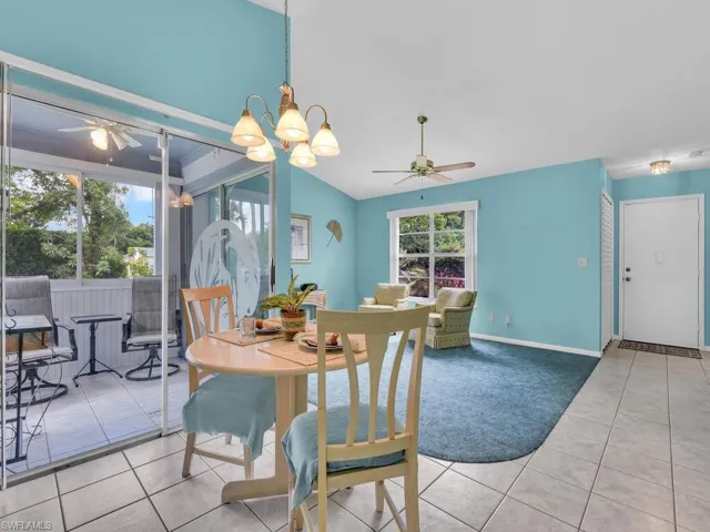 Carpeted dining room with a ceiling fan, tile patterned floors, lofted ceiling, and a chandelier