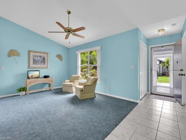 Sitting room with lofted ceiling, a ceiling fan, carpet, and tile patterned floors