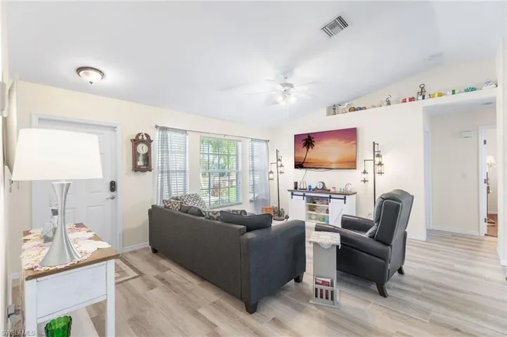 Living room featuring vaulted ceiling, ceiling fan, and light hardwood / wood-style flooring