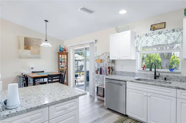 Kitchen with sink, light wood-type flooring, white cabinetry, dishwasher, and pendant lighting