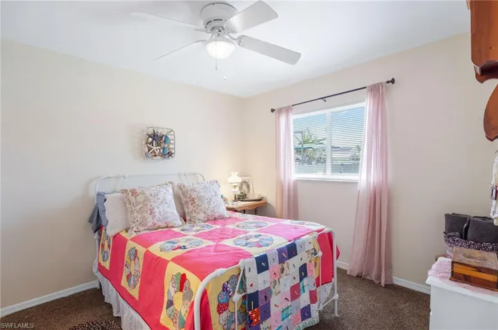 Bedroom with ceiling fan and dark colored carpet