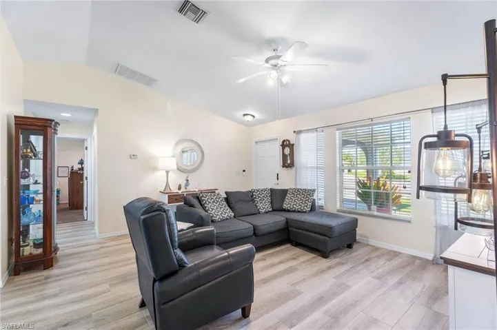 Living room featuring lofted ceiling, ceiling fan, and light hardwood / wood-style flooring