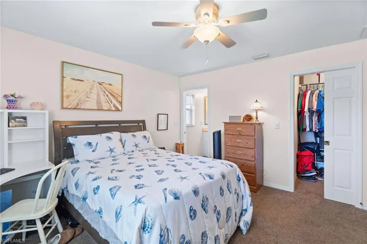 Bedroom with a closet, ceiling fan, a spacious closet, and carpet floors