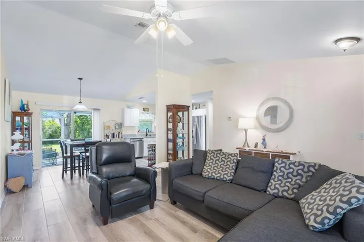 Living room with ceiling fan, vaulted ceiling, sink, and light hardwood / wood-style floors