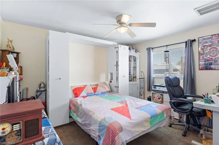 Bedroom with ceiling fan and dark colored carpet