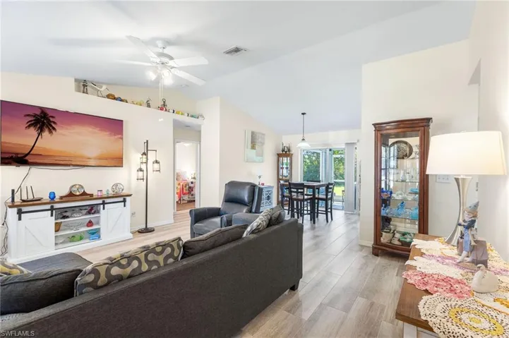 Living room with light wood-type flooring, vaulted ceiling, and ceiling fan