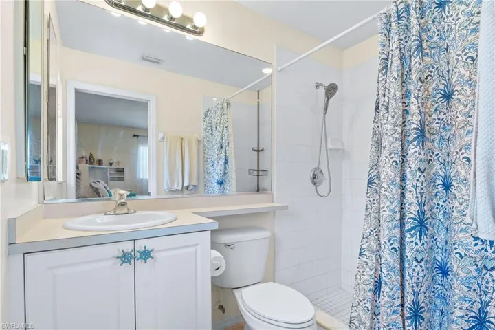 Bathroom featuring a shower with curtain, vanity, and toilet