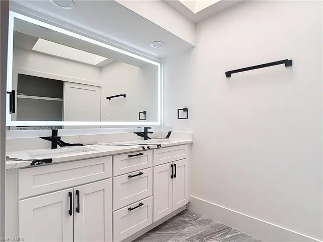 Bathroom featuring double vanity and light marble finish flooring