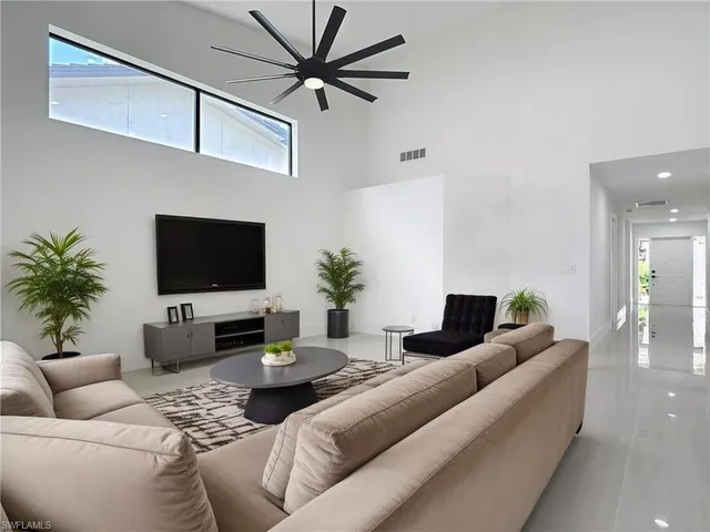 Living area with healthy amount of natural light, a ceiling fan, a towering ceiling, light tile patterned flooring, and recessed lighting
