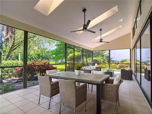 Sunroom featuring a skylight, outdoor dining space, tile patterned floors, expansive windows, and high vaulted ceiling