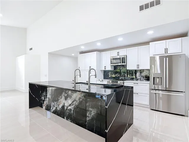 Kitchen featuring light tile patterned floors, appliances with stainless steel finishes, tasteful backsplash, recessed lighting, and a kitchen island with sink