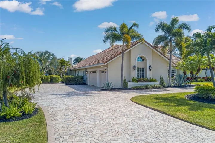 View of front of house featuring curved driveway, stucco siding, an attached garage, a front yard, and a tiled roof