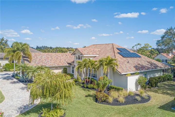 View of side of property with solar panels, stucco siding, a tile roof, and a yard