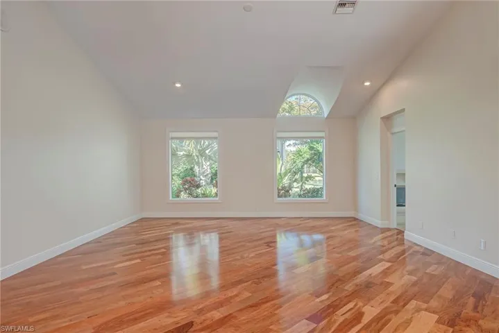 Empty room featuring lofted ceiling, cherry wood flooring