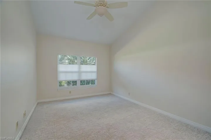 Carpeted spare room with vaulted ceiling and a ceiling fan