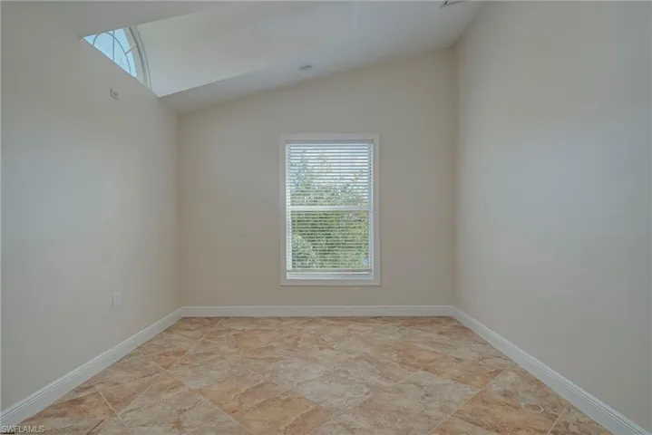 Spare room with vaulted ceiling and baseboards