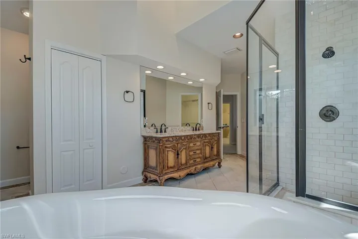 Full bathroom with a closet, double vanity, a stall shower, recessed lighting, and a freestanding tub
