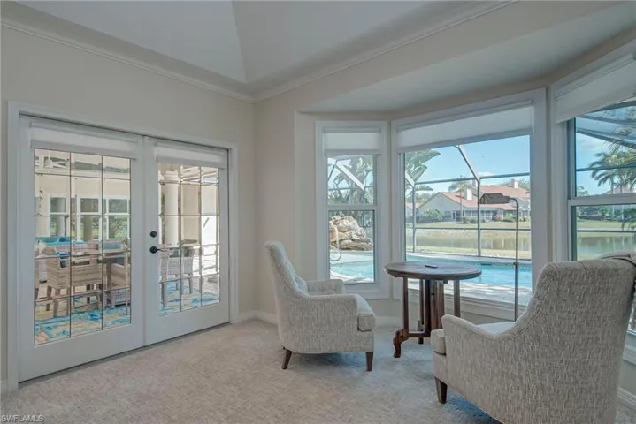Living area featuring ornamental molding, light colored carpet, french doors, and a water view