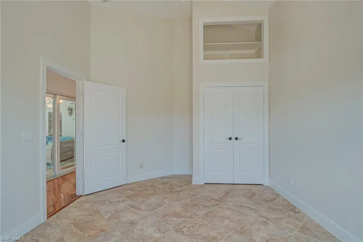 Unfurnished bedroom with a high ceiling, a closet, and light tile patterned flooring