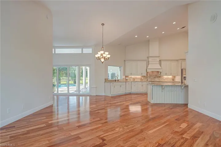 Unfurnished living room with suspended lighting, light wood-style flooring, and vaulted ceiling