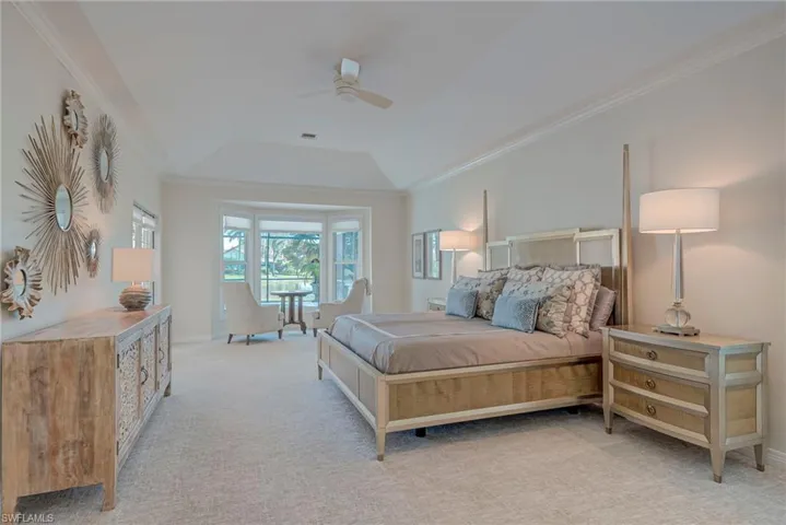 Carpeted bedroom featuring ornamental molding, a ceiling fan, and a tray ceiling