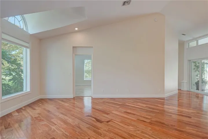 Spare room with vaulted ceiling, cherry wood finished floors, and recessed lighting