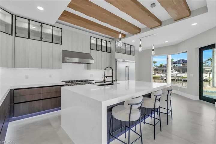 Kitchen featuring modern cabinets, stainless steel built in refrigerator, a kitchen island with sink, a kitchen breakfast bar, and recessed lighting