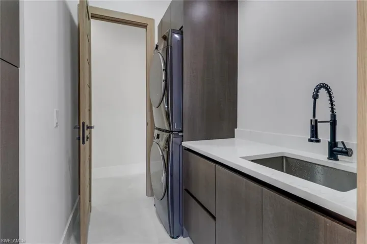 Kitchen featuring stainless steel built in fridge, modern cabinets, range hood, a kitchen island with sink, and recessed lighting