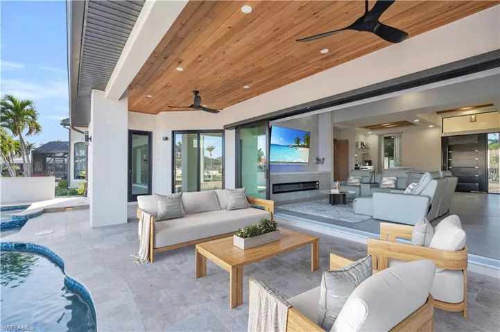 View of swimming pool featuring a ceiling fan, a water view, a patio area, a pool with connected hot tub, and an outdoor living space