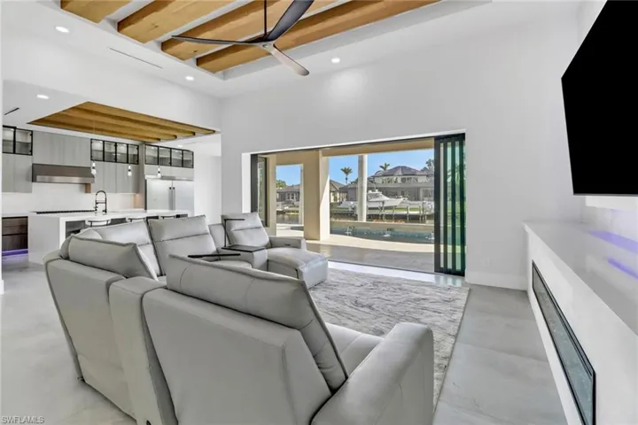 Kitchen featuring modern cabinets, high quality appliances, exhaust hood, light stone counters, and tasteful backsplash