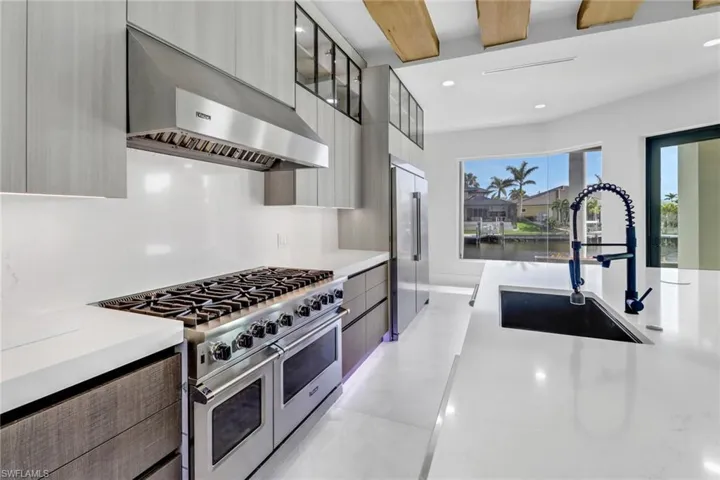 Kitchen featuring modern cabinets, appliances with stainless steel finishes, a spacious island, finished concrete floors, and range hood