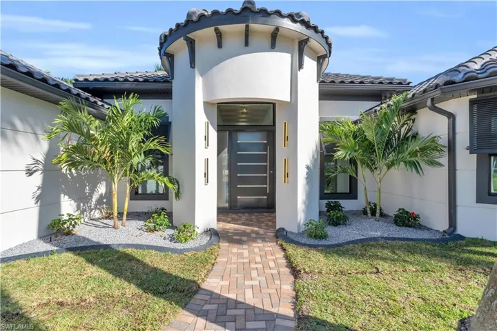 View of front facade featuring stucco siding, a front yard, a garage, and decorative driveway