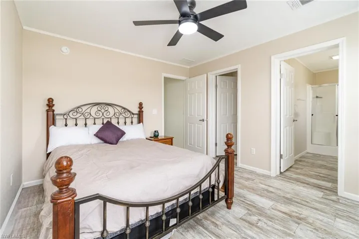 Living room with ornamental molding, light wood-type flooring, and a ceiling fan