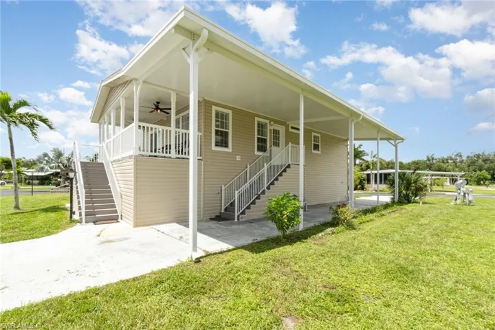 Side of house with stairs, ceiling fan, a lawn, a porch, and a carport