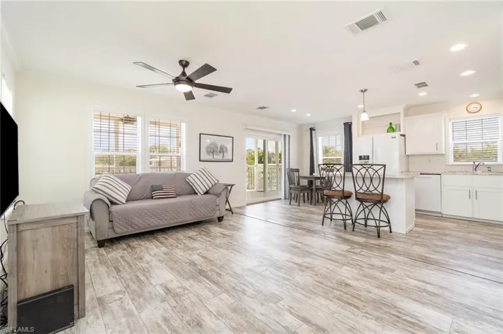 Kitchen featuring white appliances, white cabinets, light countertops, light wood-style flooring, and open shelves