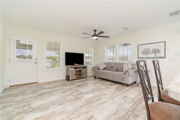 Living area featuring healthy amount of natural light, light wood-style floors, crown molding, a ceiling fan, and recessed lighting