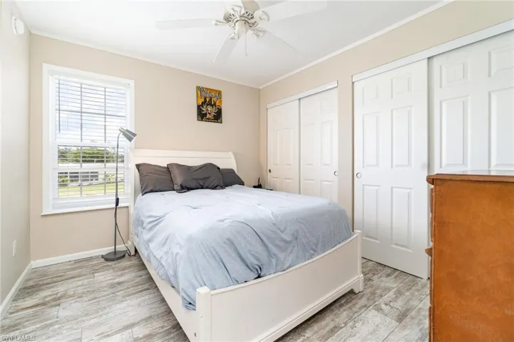 Full bathroom featuring vanity, a shower stall, light wood-style floors, and crown molding