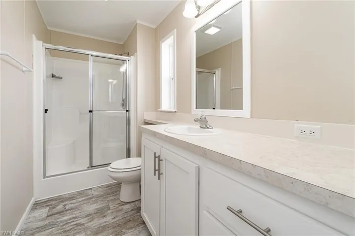 Bedroom with ornamental molding, a ceiling fan, light wood-style flooring, and connected bathroom