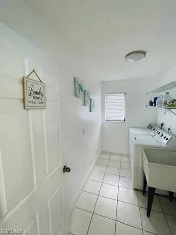 Washroom with independent washer and dryer and light tile patterned flooring