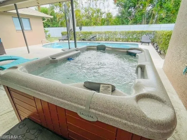 View of pool featuring a hot tub, a fenced backyard, and a patio