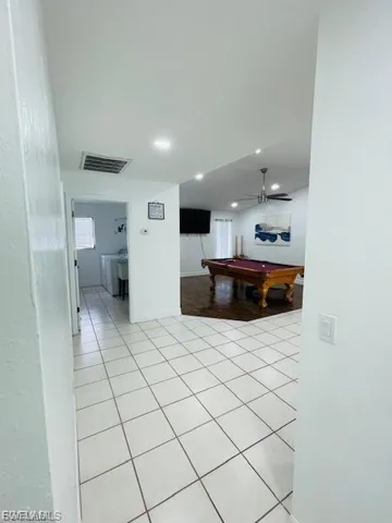 Corridor featuring washing machine and clothes dryer, light tile patterned flooring, and recessed lighting