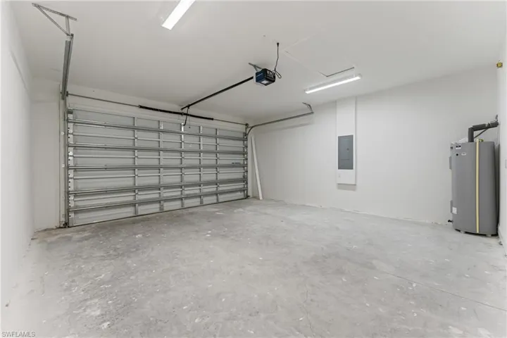 Garage featuring electric panel, water heater, and a garage door opener