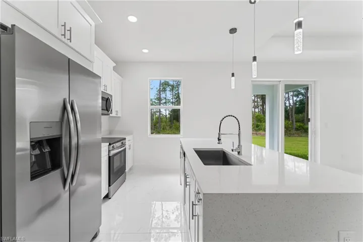 Kitchen with a kitchen island with sink, recessed lighting, a sink, marble finish floor, and appliances with stainless steel finishes