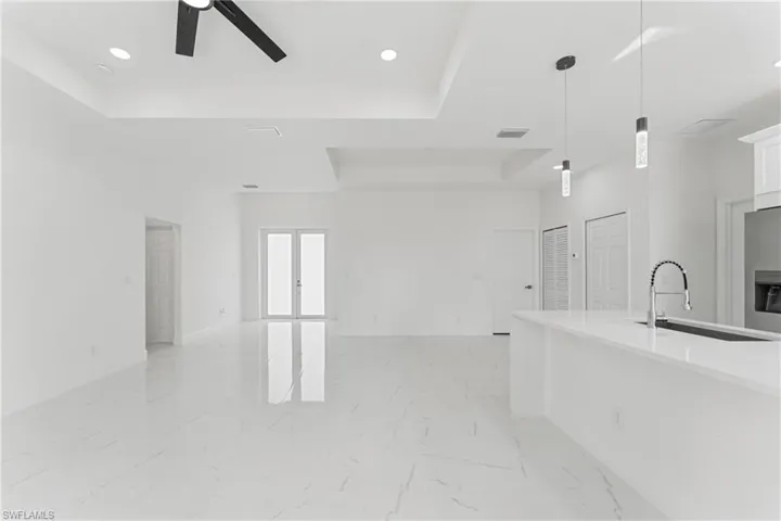 Kitchen with white cabinets, marble finish floor, a tray ceiling, and open floor plan