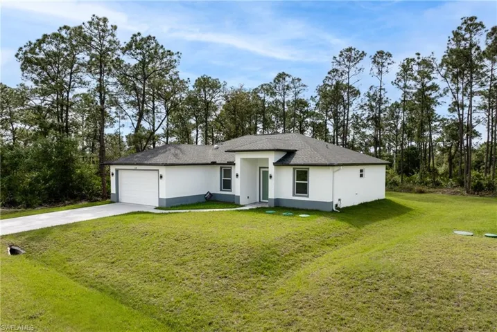 View of front of home with a garage, driveway, a front lawn, and stucco siding