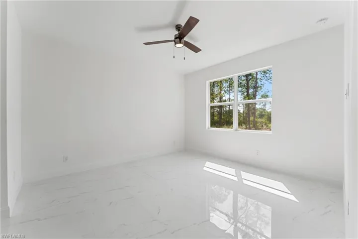 Empty room with marble finish floor, baseboards, and a ceiling fan