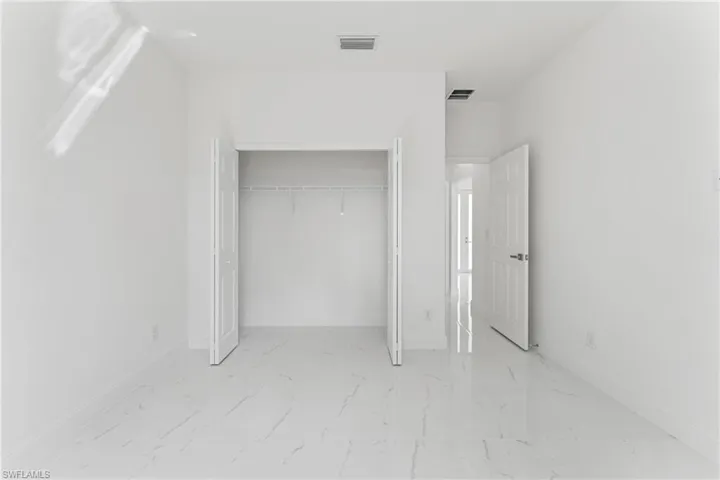 Unfurnished bedroom featuring a closet, marble finish floor, visible vents, and baseboards