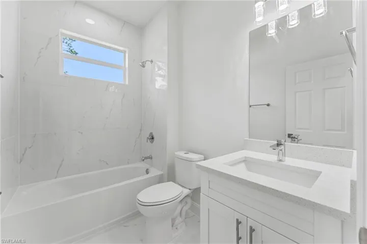 Full bath featuring marble finish floor,  shower combination, vanity, and toilet